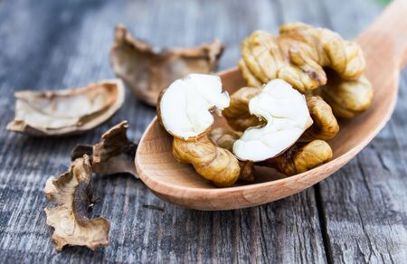 Walnuts and walnut kernels lie in a spoon on a rustic old wooden table. Kernels of walnuts. Harvest...