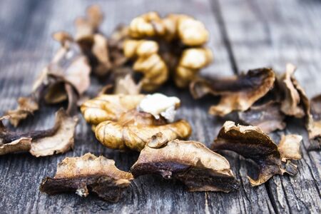 Walnut kernels and partitions near whole walnuts on a wooden table. The medicine for tinctures and...