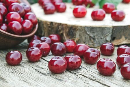 Red cherry scattered on old wooden boards. Juicy delicious fruit. Close-up.