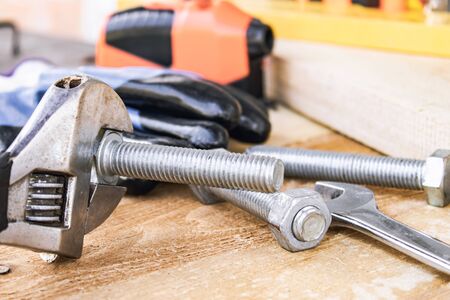 An adjustable spanner lies near the bolts and nuts of the washer against the background of wooden...
