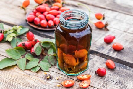 Tincture or drink with wild rose in a glass bottle near ripe red rosehip berries. Phytotherapy.の写真素材