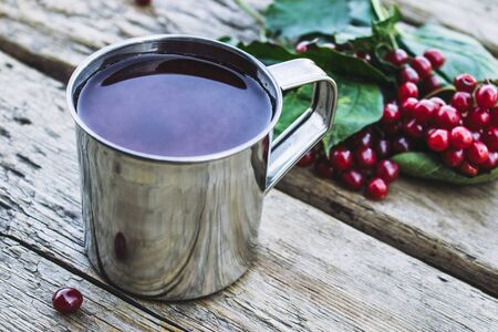 Mug or cup of hot viburnum tea on a wooden table next to red viburnum berries. Source of natural vitamins. Used in folk medicine. Close-up.の写真素材