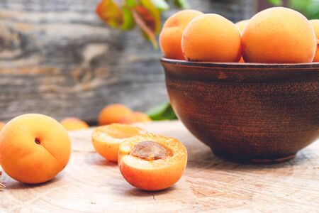 Ripe yellow apricots in a bowl on a wooden table near the apricot. Close-up.の写真素材