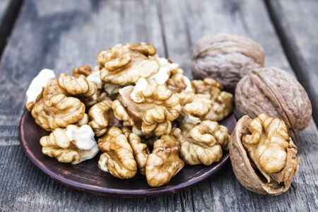 Walnut kernels lie in a bowl on a rustic old wooden table. Fresh walnuts. Harvest walnuts.の写真素材