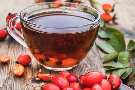 Cup of rosehip tea with fresh berries on a wooden table. Phytotherapy.の写真素材
