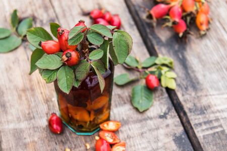 Tincture in a glass bottle with red rosehip berries on a wooden table. Phytotherapy.の写真素材