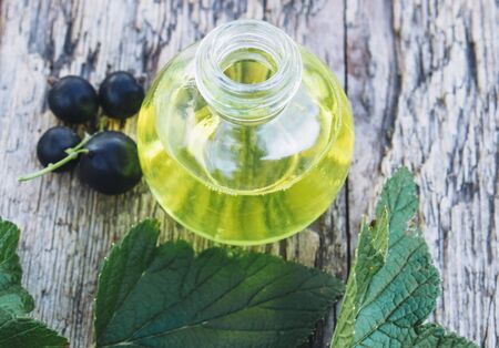 Black currant oil in a bottle on the background of old boards. Cold remedy extract of black currant. Close-up.の写真素材