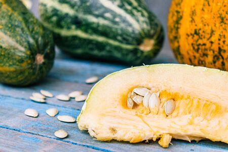 Ripe orange pumpkin sliced with seeds on blue old boards. Autumn harvest.の写真素材
