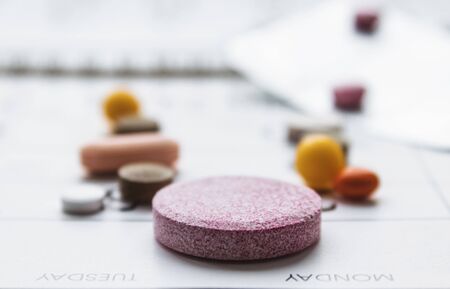 A bunch of different pills on a calendar background. Pills, supplements and medicines for the...