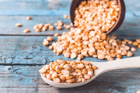 Dry yellow peas in a wooden spoon on old boards. Chipped yellow peas are used for cooking. Close-up.