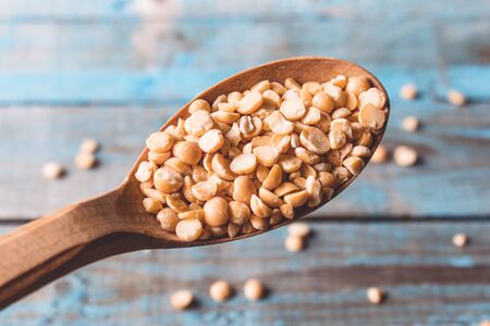 Dry yellow peas in a wooden spoon on old boards. Chipped yellow peas are used for cooking. Close-up.の写真素材