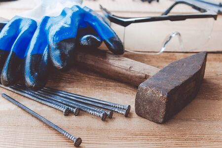 Old hammer with nails with blue gloves and glasses to protect the eyes on a blackboard background....