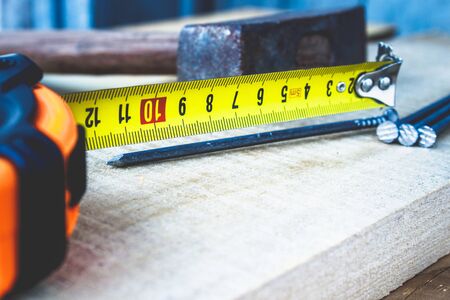 Old hammer with nails and a yellow ruler of roulette on a blackboard background. Tools for...
