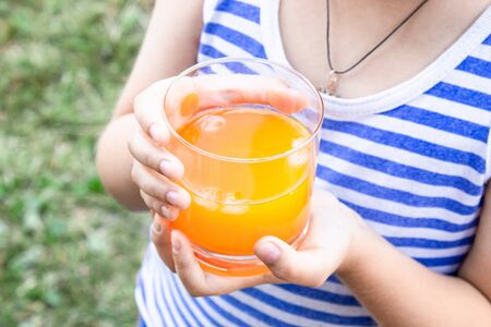 A little boy drinks juice with ice in nature. Close-up.の写真素材