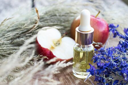 Bottle of apple essential oil and fresh apples on a wooden table. Essential oil is used to fill lamps, perfumes and in cosmetics. Close-up.の写真素材
