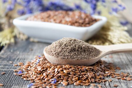 Crushed flax seed in a wooden spoon on a pile of flaxseed. Ground seed is used to prevent heart disease and being overweight.の写真素材
