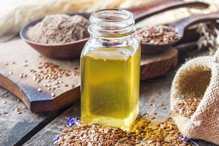 Flaxseed oil in a jar next to flax seeds on a background of old boards. Flaxseed oil is used in cooking, medicine, cosmetology.の写真素材
