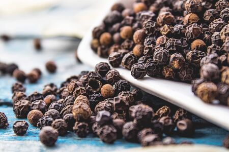 The black pepper is scattered on blue boards. Black pepper spices and seasonings for cooking.