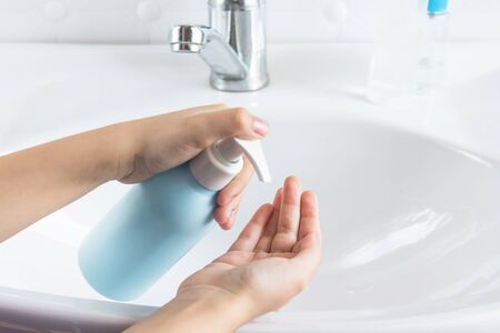 A child washes his hands near a white sink. The concept of hand hygiene and disinfection, healthcare and hand washing.の写真素材