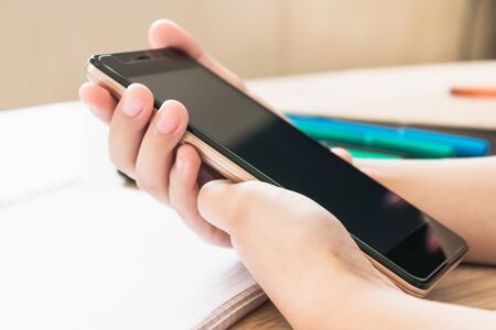 A child is learning distance learning lessons on a mobile phone. The concept of distance learning and online learning.の写真素材