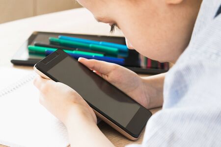 A child is learning distance learning lessons on a mobile phone. The concept of distance learning...