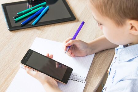 A child is learning distance learning lessons on a mobile phone. The concept of distance learning and online learning.の写真素材
