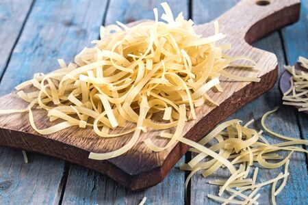 Dry pasta on a cutting board on a background of blue boards. Healthy eating or healthy lifestyle.の写真素材