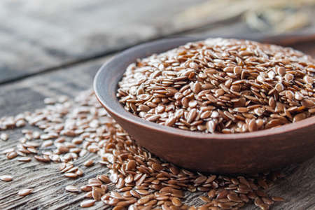 Flax seeds lie on old boards and in a spoon on a wooden table. Flaxseed is used to prevent heart disease and being overweight.の写真素材
