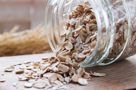 Gray oatmeal scattering from a can on a cutting board. The concept of a healthy diet, breakfast.の写真素材