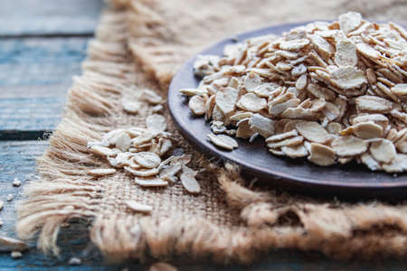 Gray oatmeal on a background of blue boards near the burlap. The concept of a healthy diet, breakfast.の写真素材