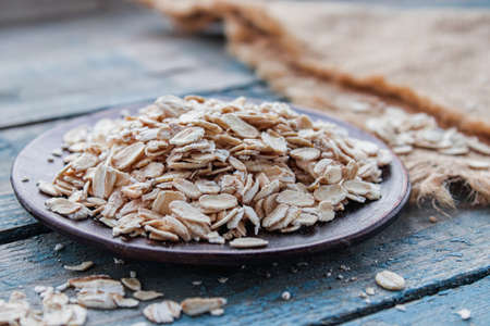 Bowl with raw oatmeal on a background of blue boards. The concept of a healthy diet, breakfast.の写真素材