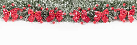 Christmas and New Year banner with red bows and berries on a white background. Christmas composition on a white background with copy space. New Year's holidays.の写真素材