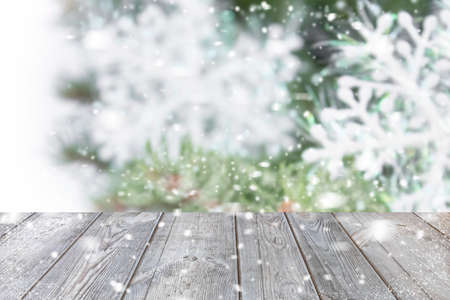 Christmas holiday background with empty wooden board against the background of a blurred Christmas tree with snowflakes. Christmas composition with copy space.の写真素材