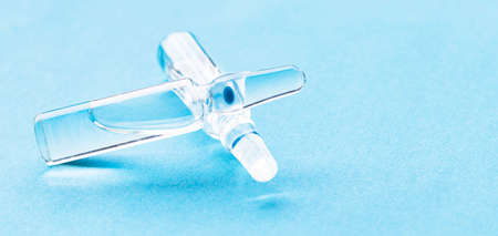 Glass medical ampoules on the table on a blue background. Medical glass ampoules close up.