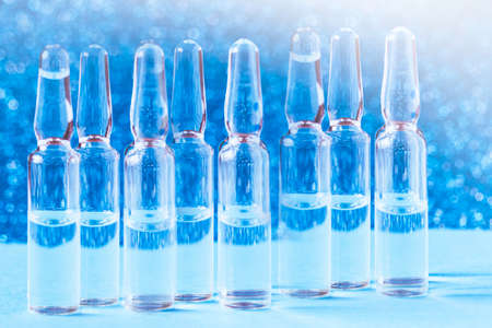 Glass medical ampoules on the table on a blue background. Medical glass ampoules close up.の写真素材