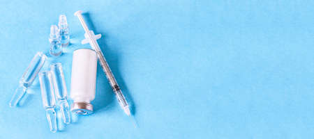 Medical ampoules for injection, vial and syringe on a blue background. Glass ampoules and vials of...