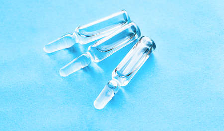 Medical ampoules for injection on a blue background. Scattered glass ampoules with medicine on the...