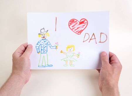 hands hold a drawing of a child. Fathers Day Congratulations Concept.の写真素材