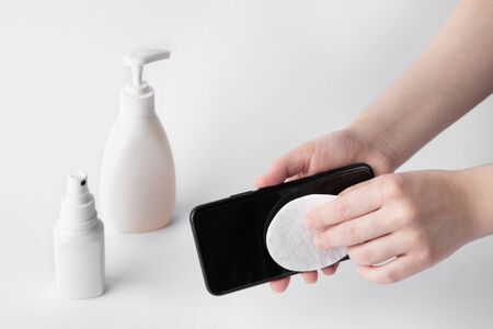 Someone wipes a black phone screen with a cotton pad to disinfect.の写真素材