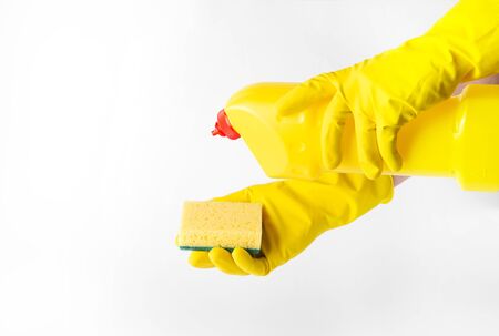 Hands in rubber gloves holding a plastic bottle with detergent and a sponge.の写真素材