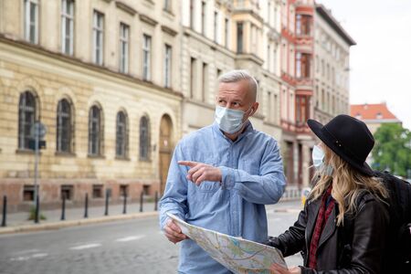 A gray-haired man in a denim shirt shows the direction to a young girl.の写真素材
