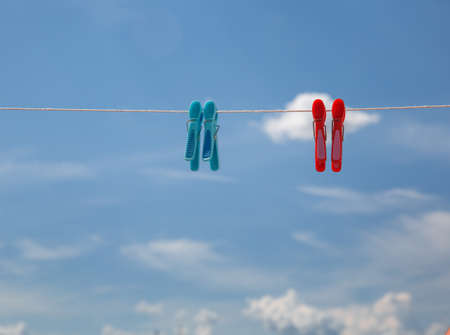 clothespins on a rope against the background of a bright blue sky with clouds