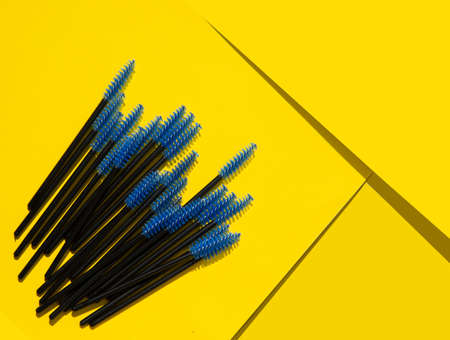 blue makeup brushes, combs for eyelashes and eyebrows on a yellow backgroundの写真素材