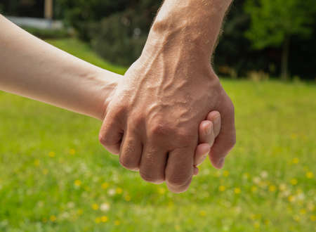 an adult hand holds a young hand. selective focusの写真素材