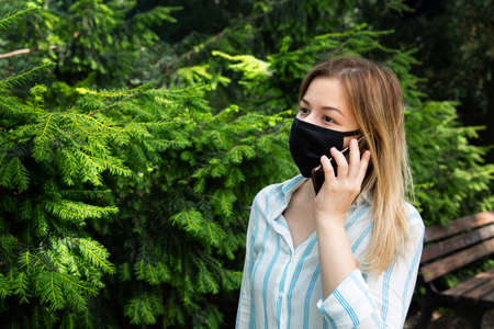 girl with blond hair talking on the phone in the park.