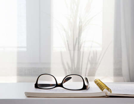 Image of an open notebook placed in bed with glasses .blurred backgroundの写真素材