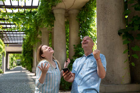 a blonde woman and a man with gray hair are happy and celebrating a victoryの写真素材