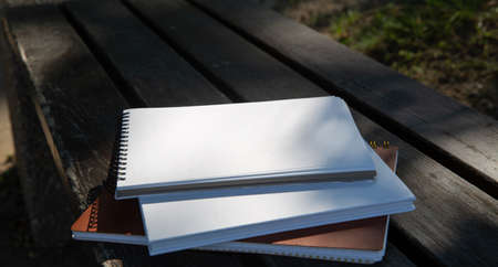 books and notebooks on a park bench on a sunny dayの写真素材