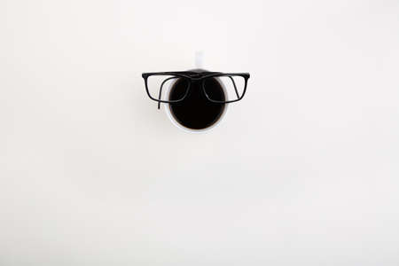 glasses lie on cup of coffee, on light background. view from above.の写真素材