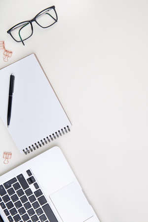 light office desk with laptop, white notebook mockup and glassesの写真素材
